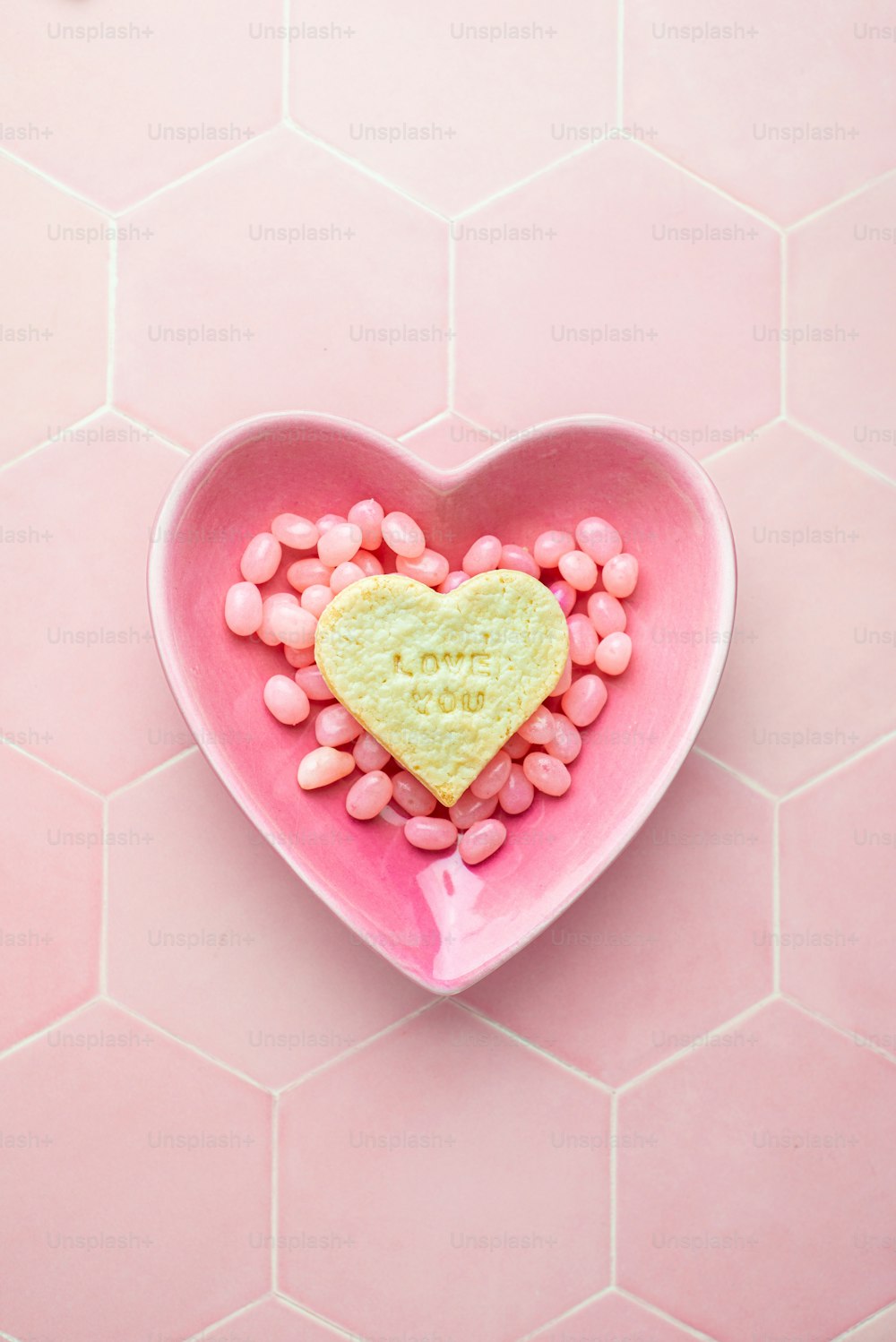 a heart shaped bowl filled with pink candy