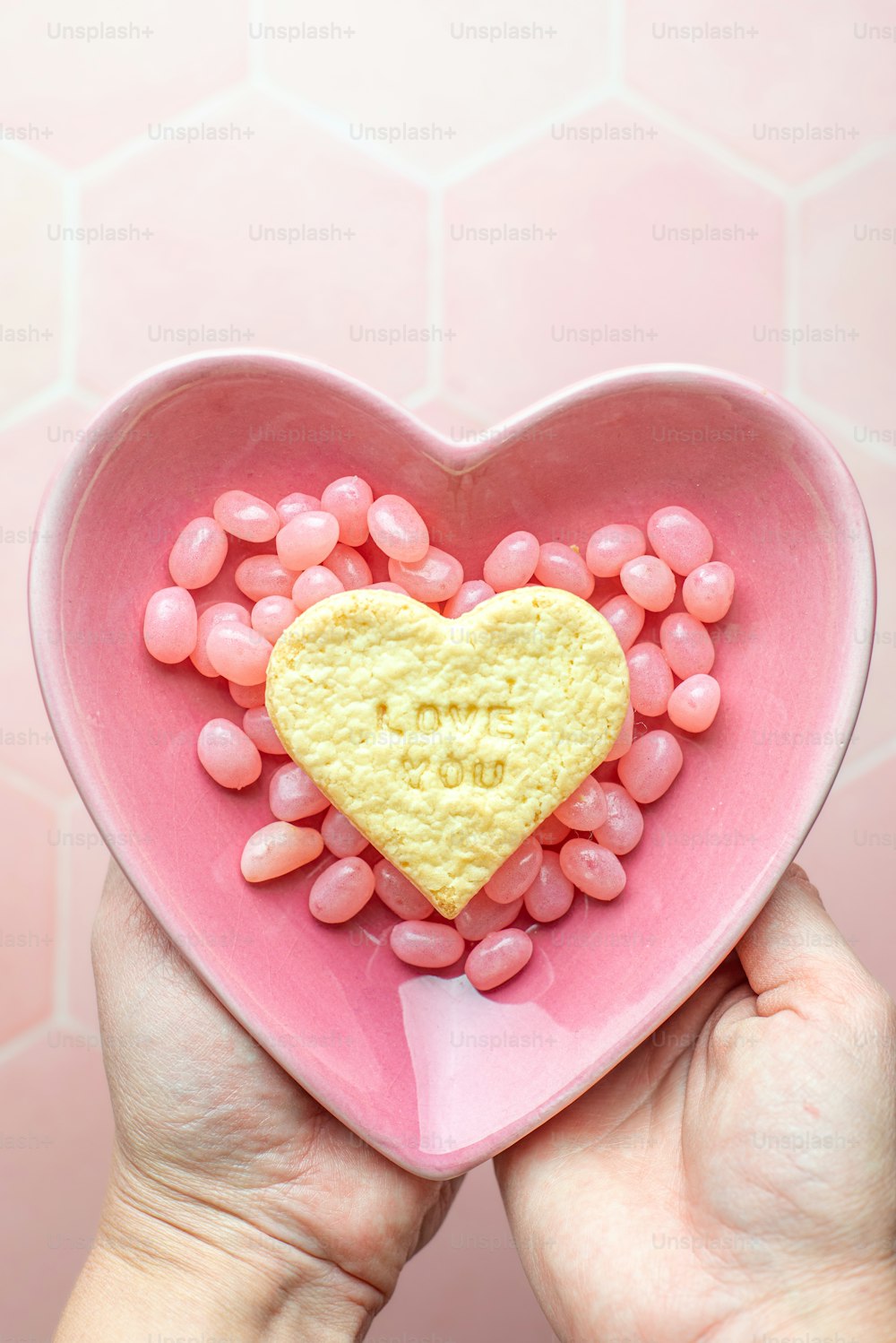 a person holding a heart shaped bowl filled with candy