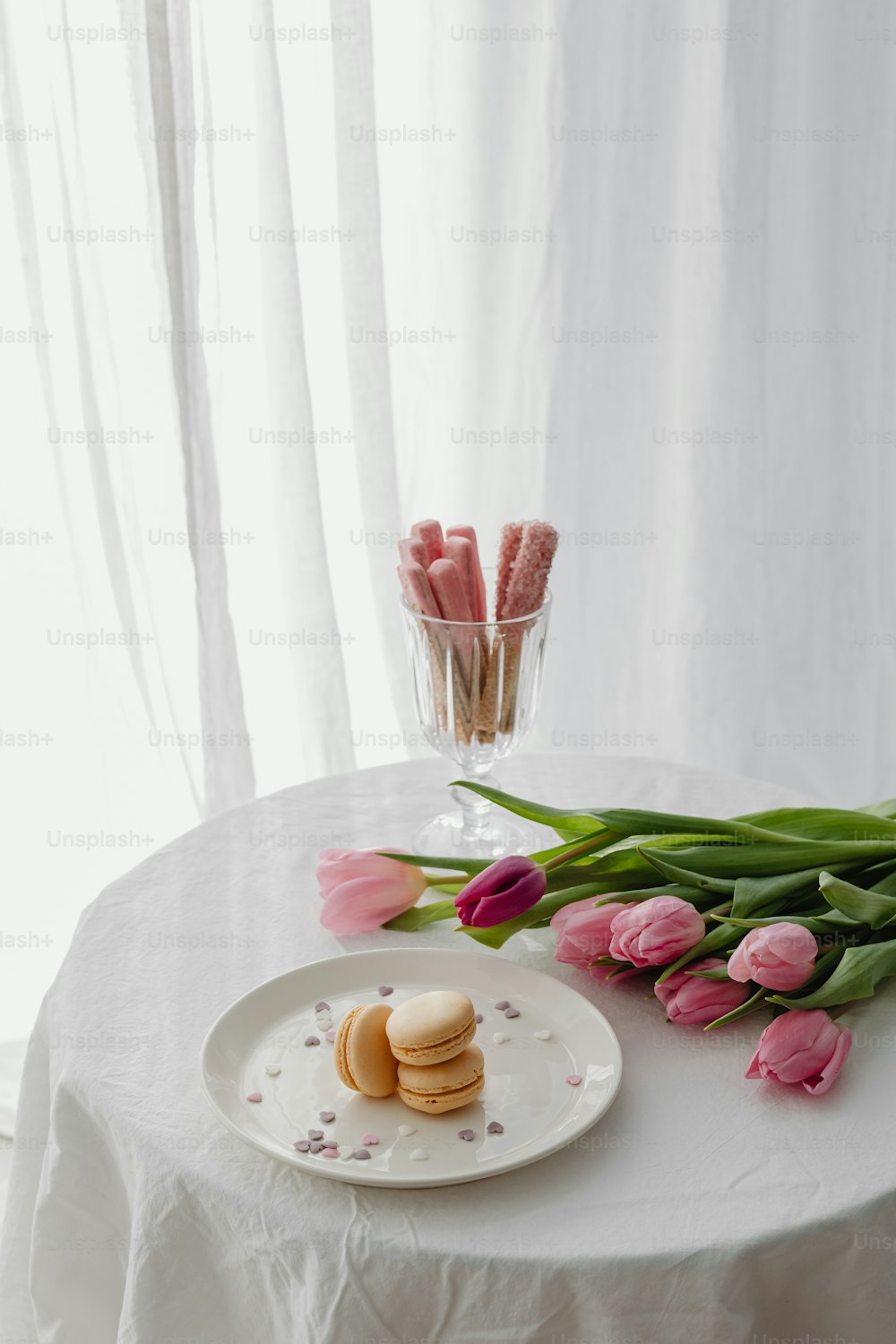 a plate of cookies and pink tulips on a table