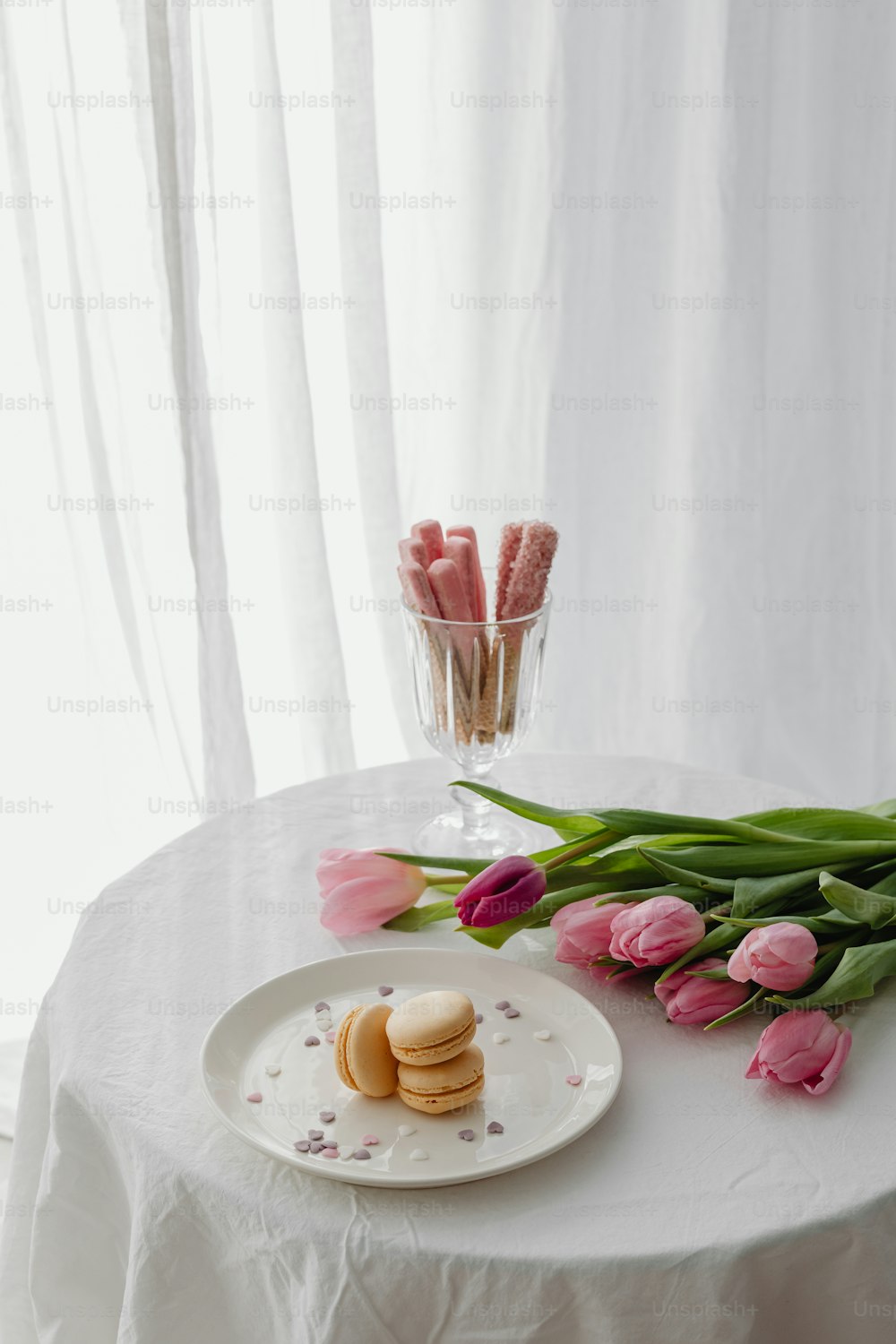 um prato de biscoitos e tulipas cor-de-rosa em uma mesa
