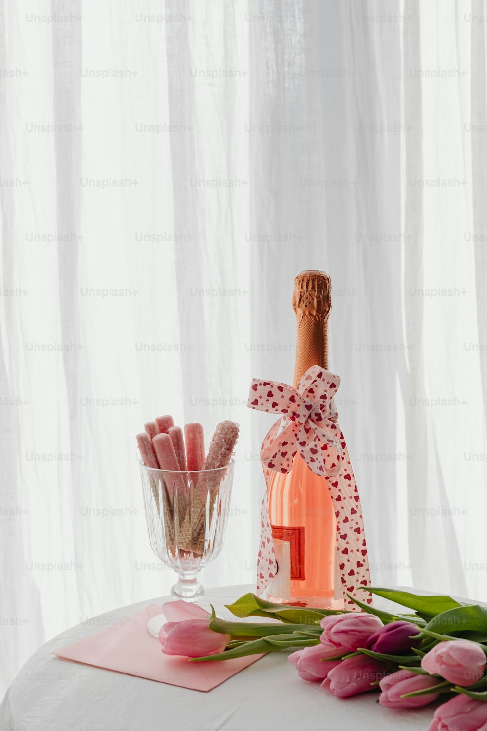 a bottle of wine and some pink tulips on a table