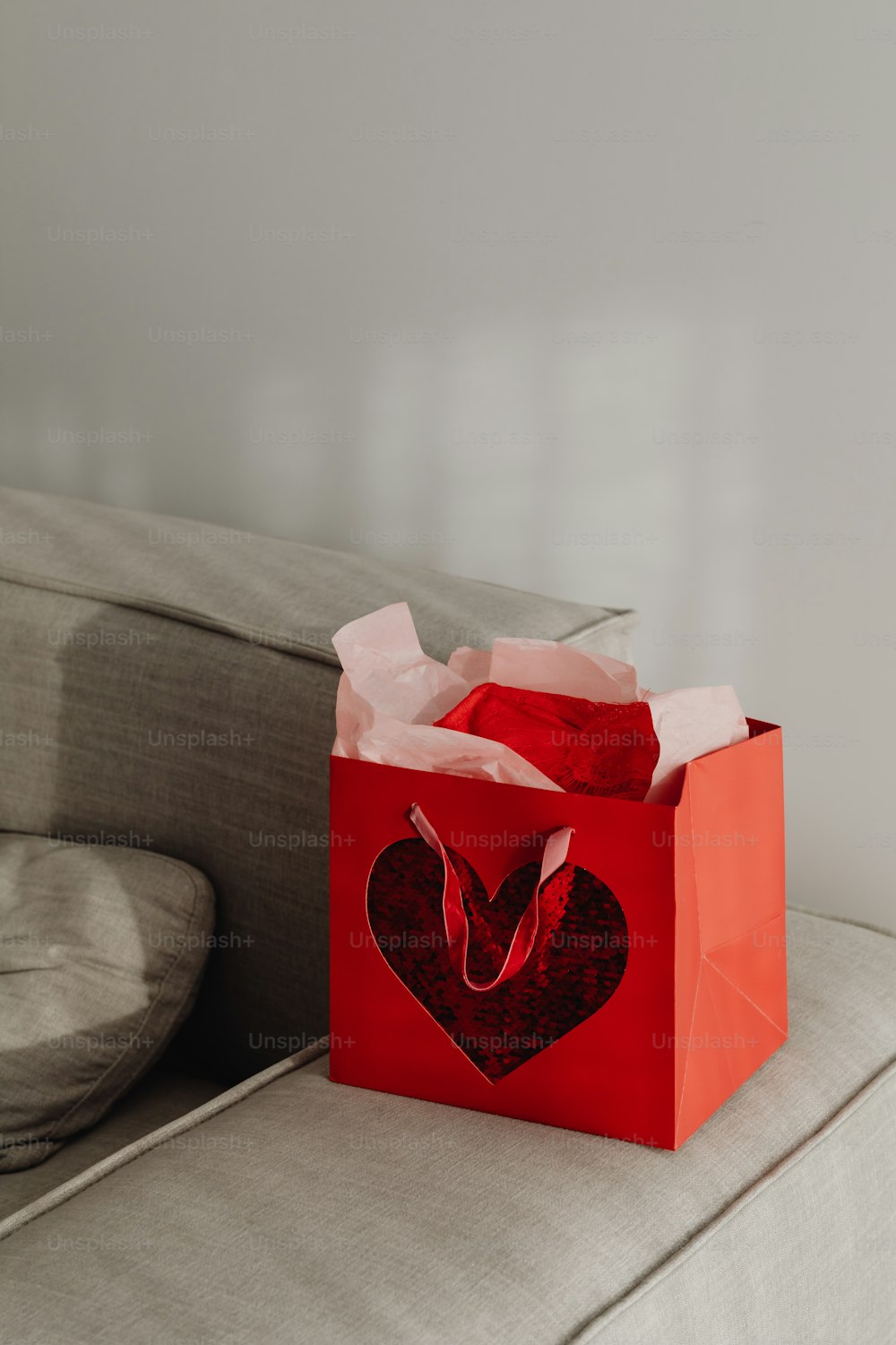 una bolsa roja con un corazón sentado en un sofá