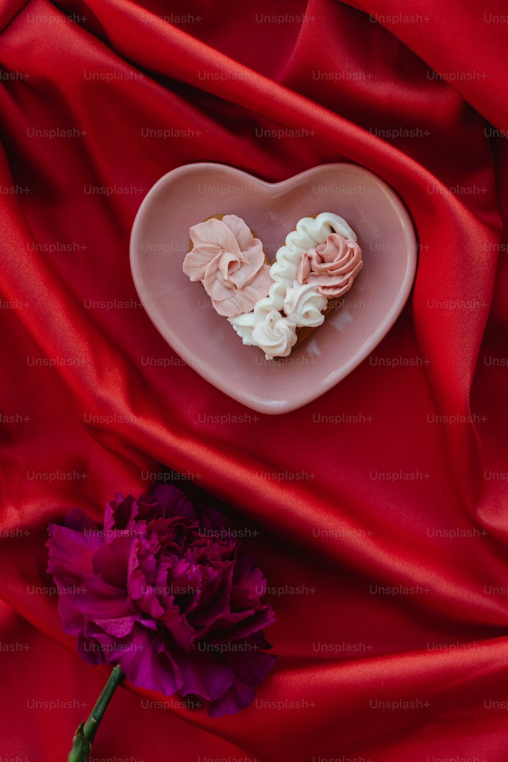ein herzförmiger Teller mit Blumen auf einem roten Tuch