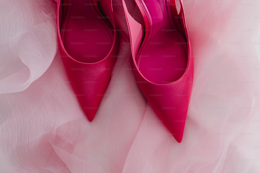a pair of pink high heeled shoes on a pink tulle