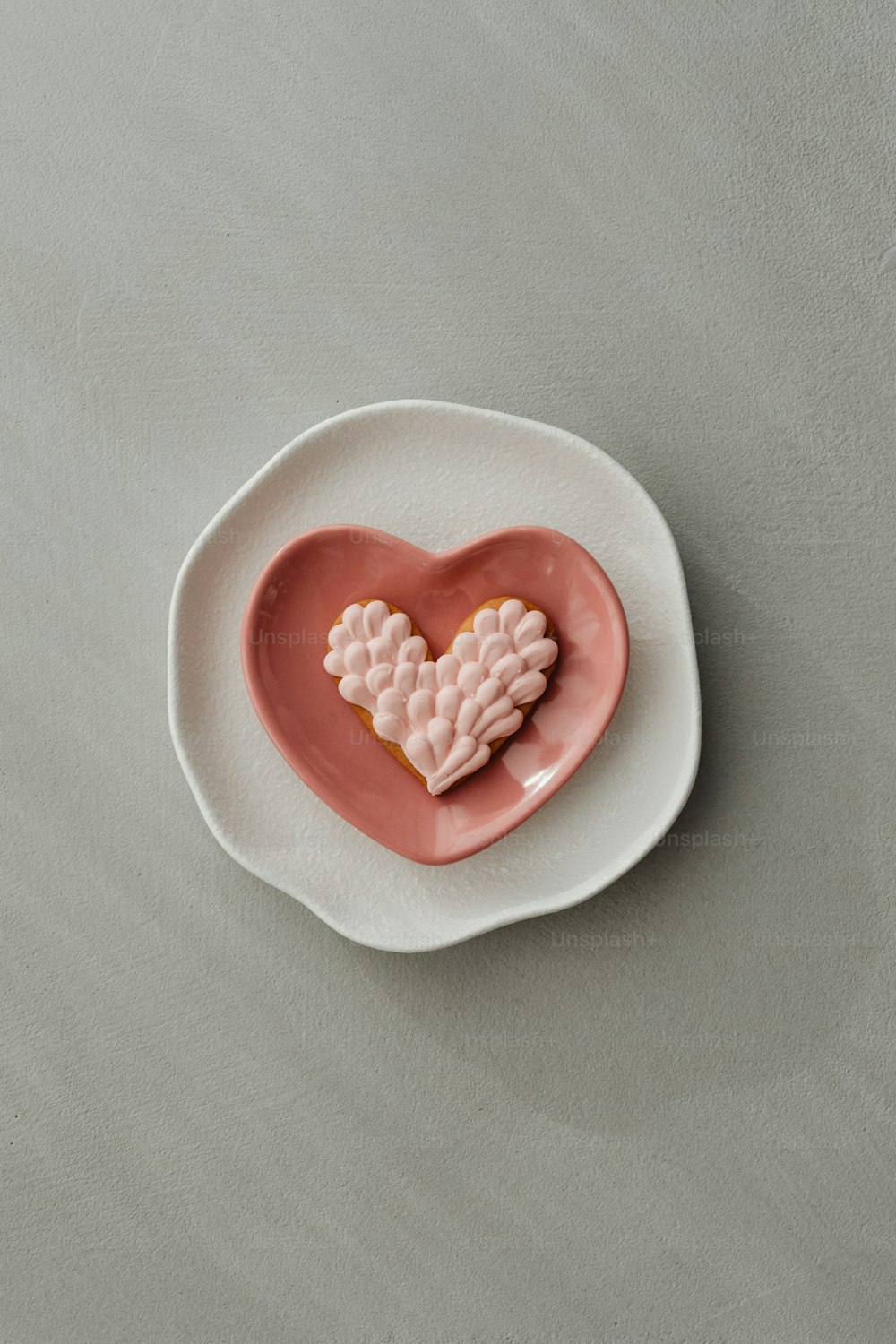 um biscoito em forma de coração sentado em cima de um prato branco