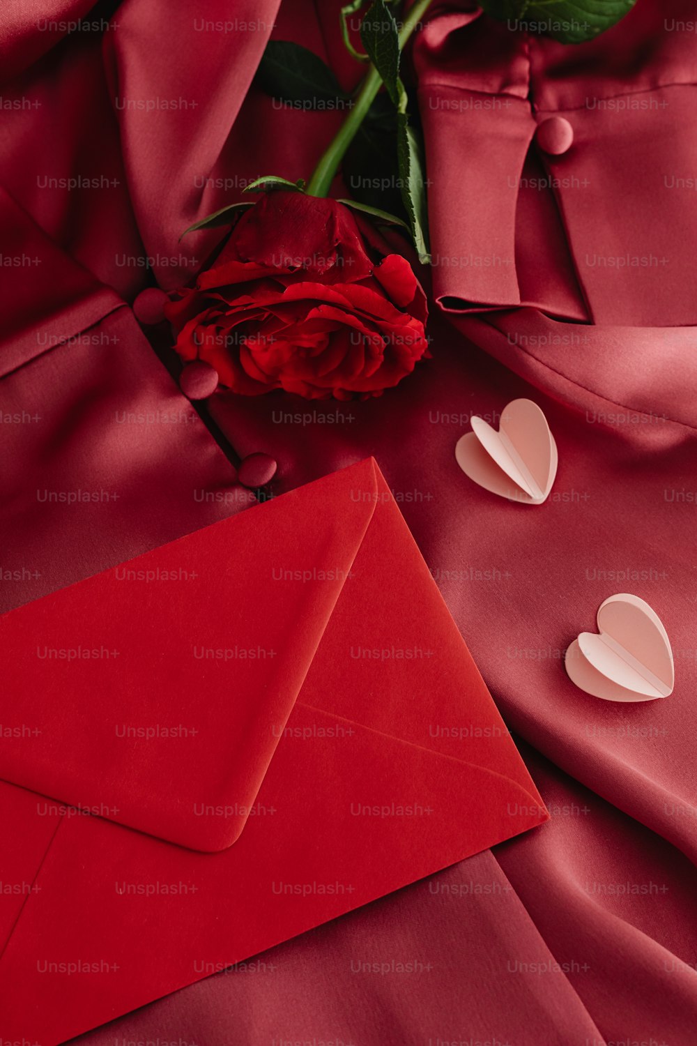 uma rosa vermelha e um envelope vermelho com corações
