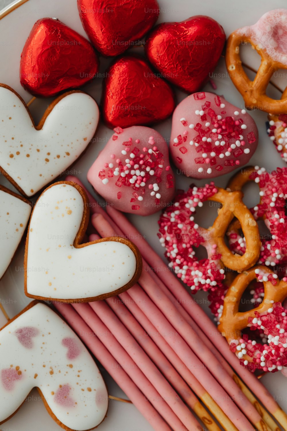um prato branco coberto com biscoitos em forma de coração e pretzels