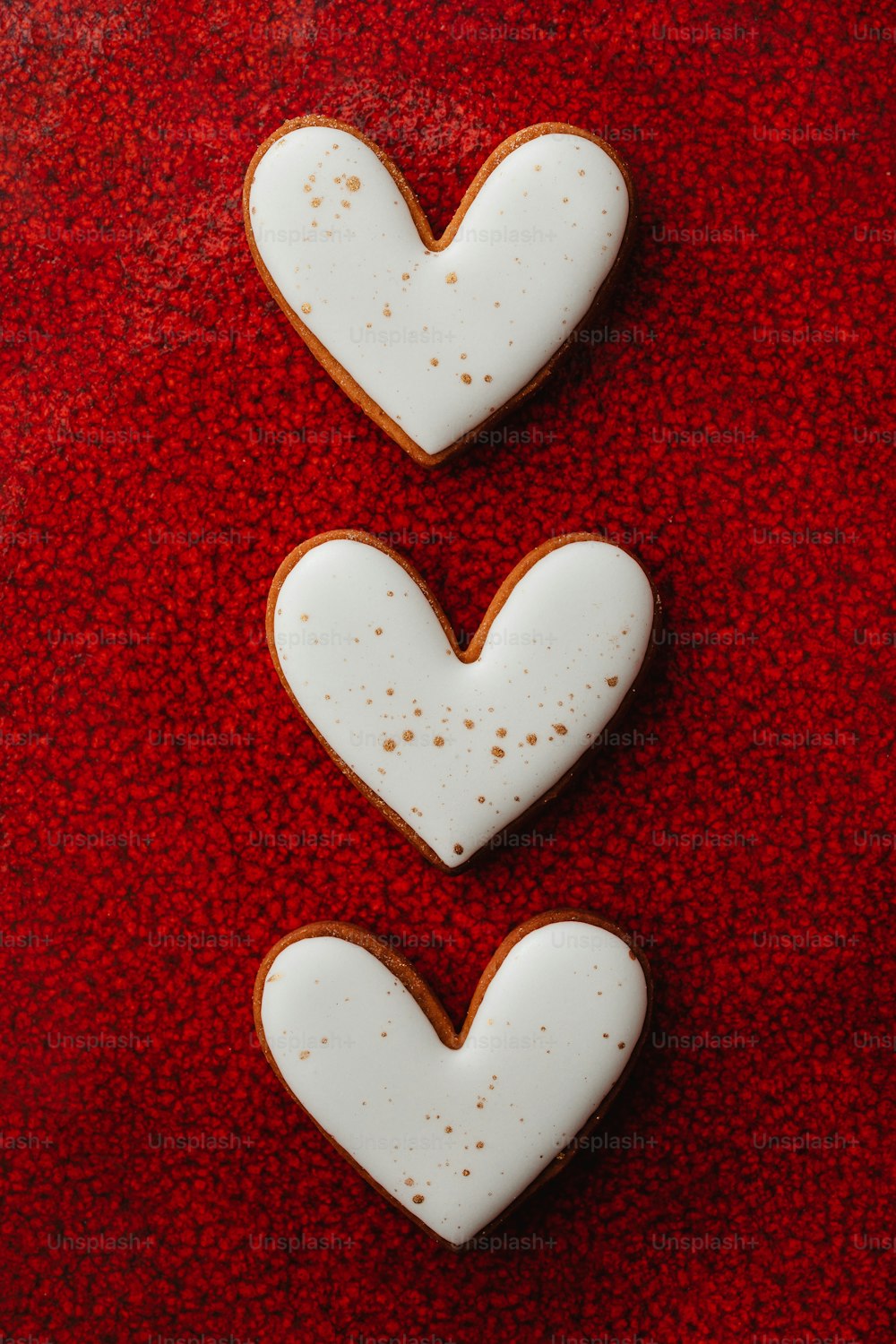 Due biscotti a forma di cuore seduti sopra una superficie rossa