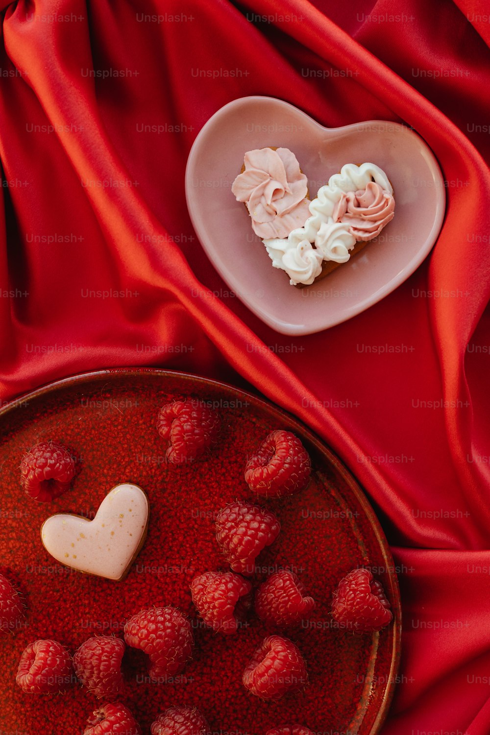 a bowl of raspberries next to a heart shaped cookie
