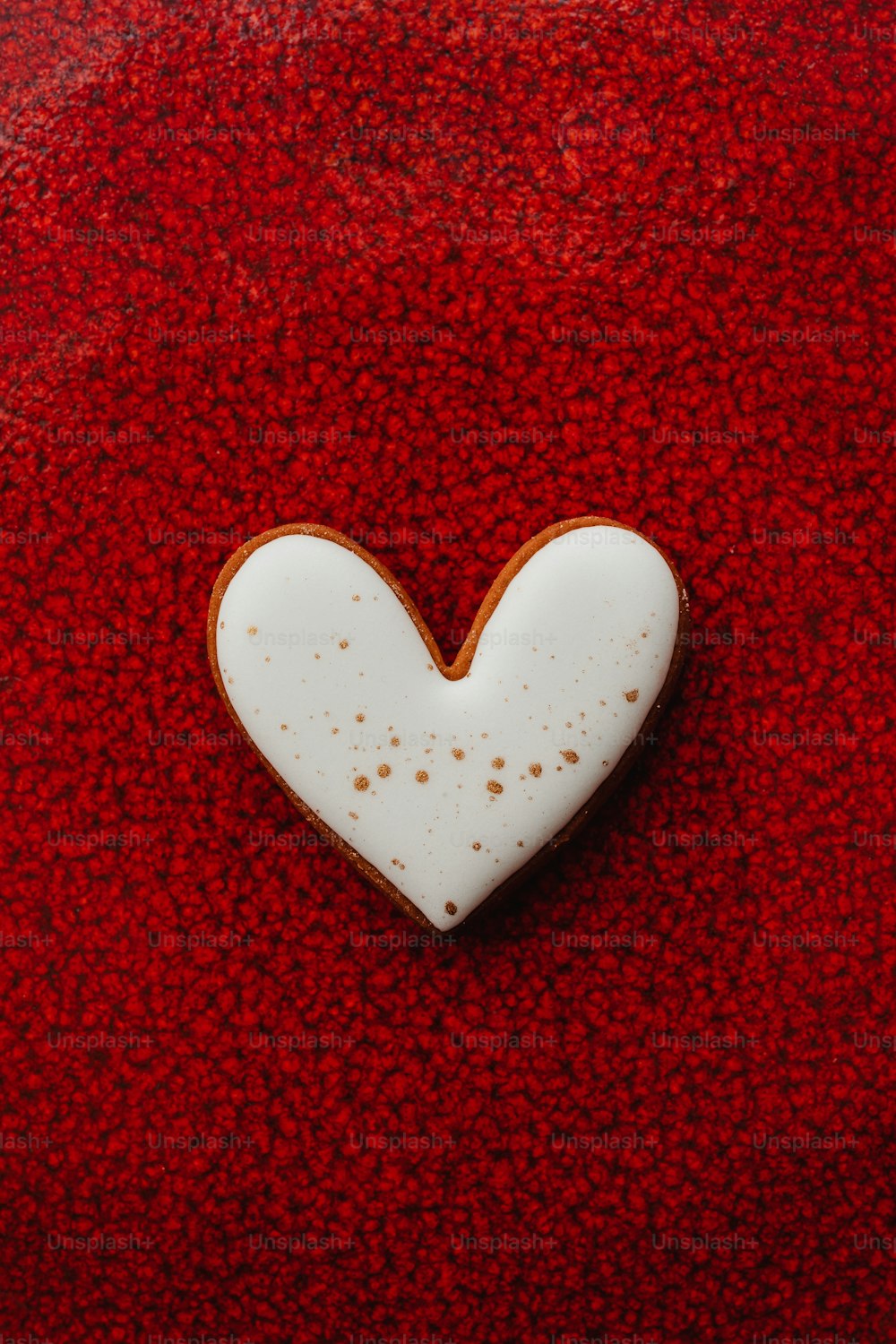 um biscoito em forma de coração sentado em cima de uma superfície vermelha
