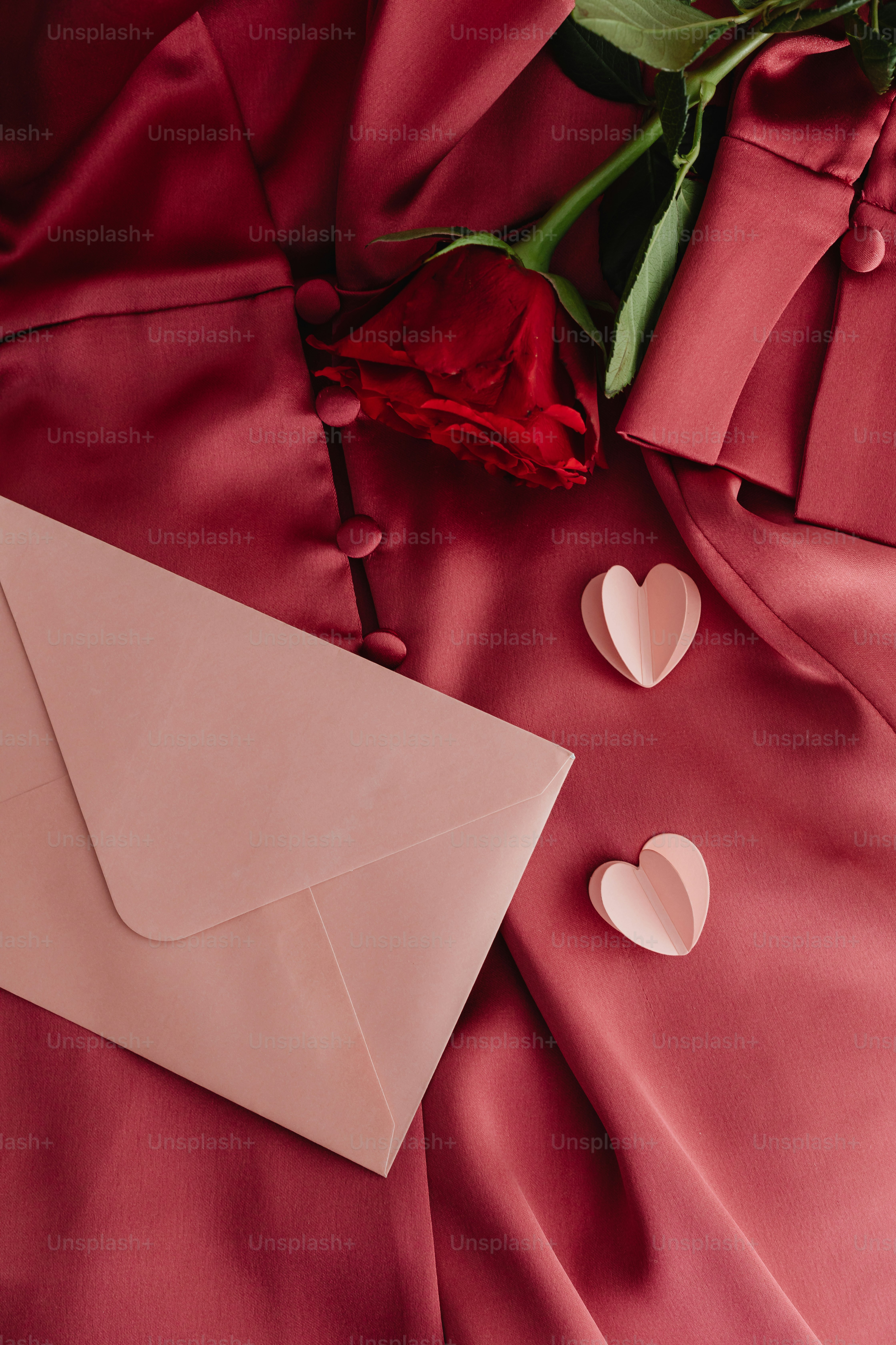 um envelope rosa com uma rosa e dois corações