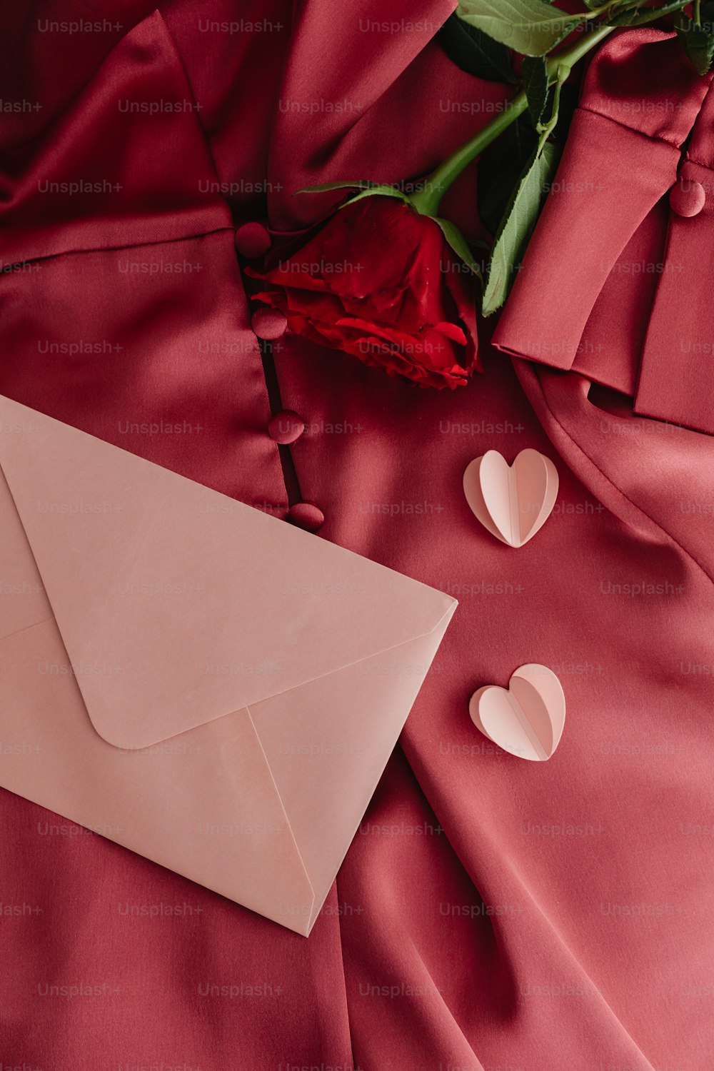 a pink envelope with a rose and two hearts