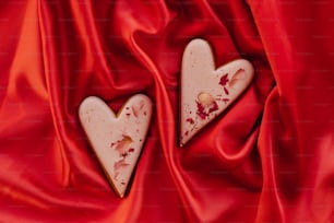 Dos galletas en forma de corazón sentadas encima de un paño rojo