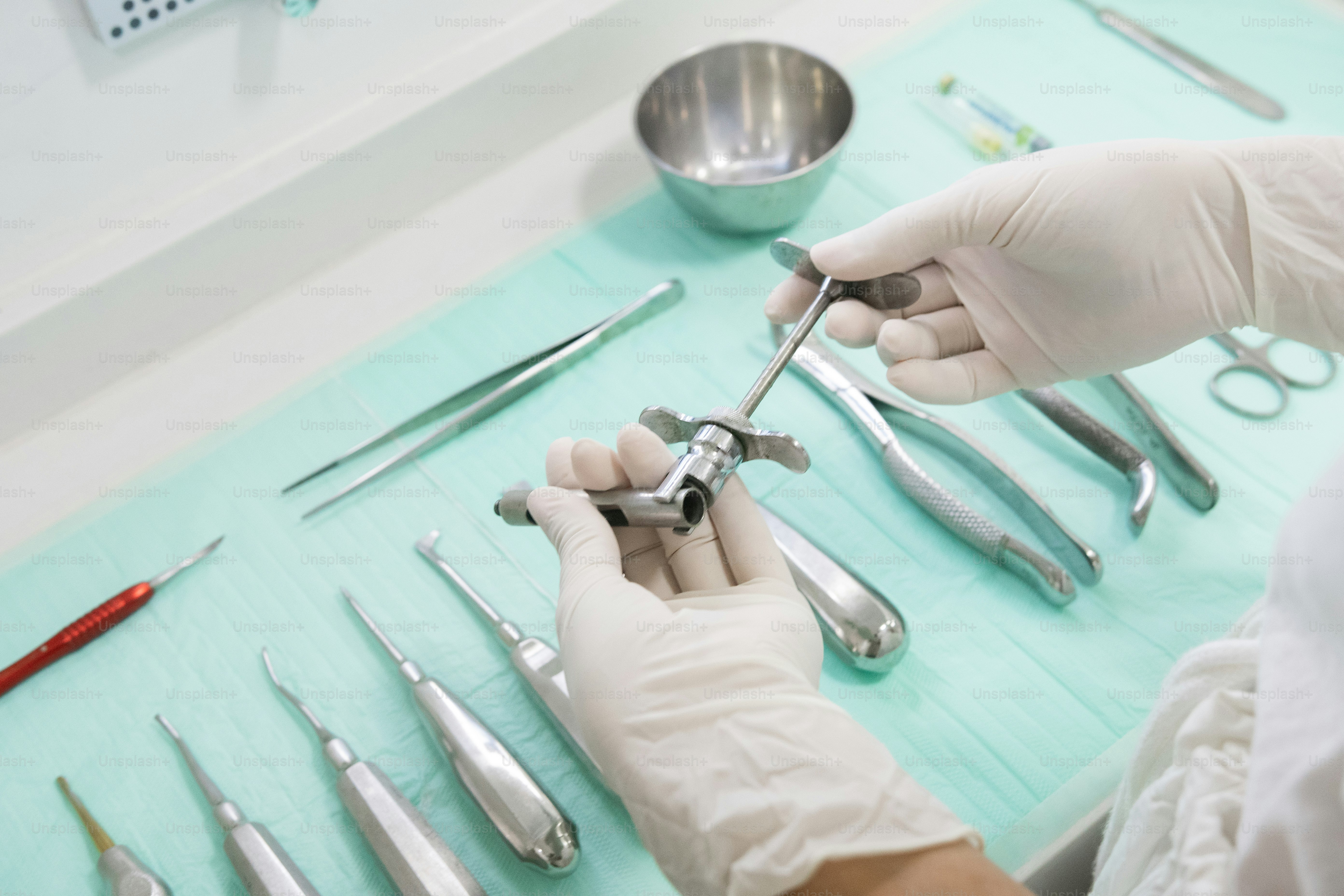 a person in white gloves holding a pair of scissors
