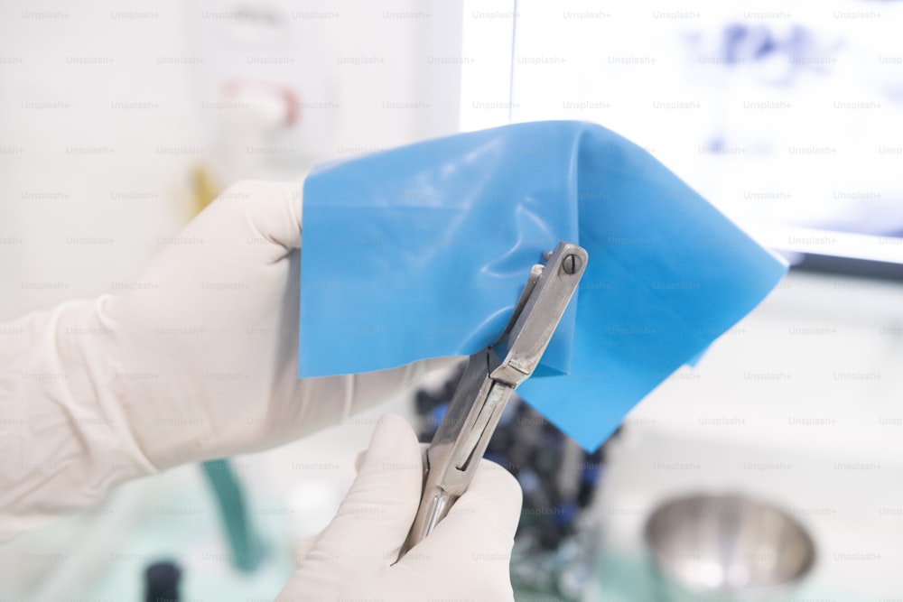 a person in white gloves holding a pair of scissors