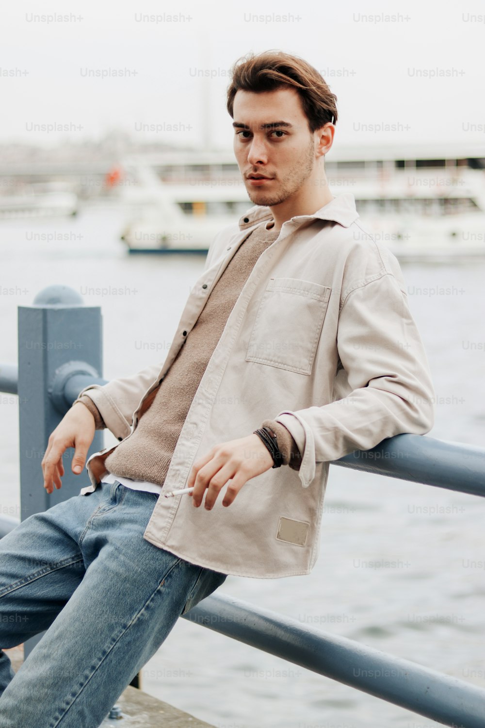 a man sitting on a rail next to a body of water