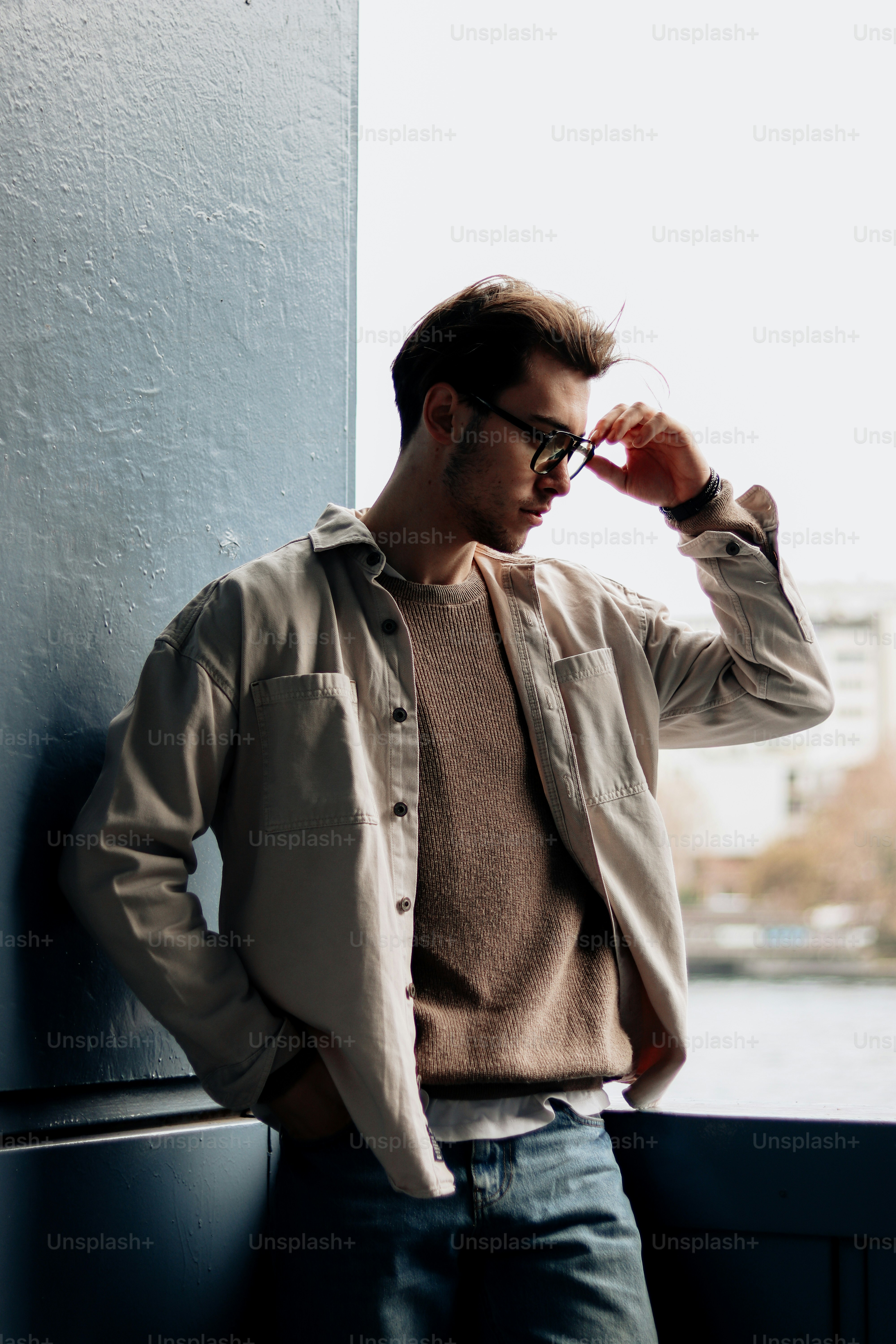 a man leaning against a wall with his hands on his head