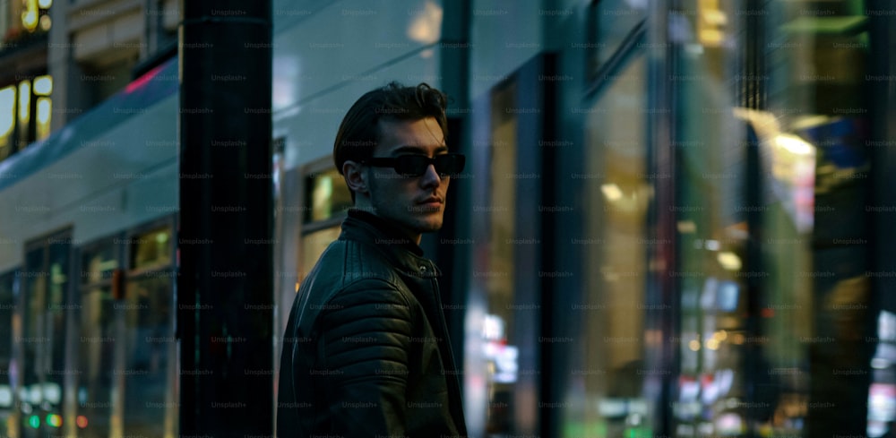 um homem usando óculos escuros de pé ao lado de um edifício