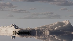 a mountain covered in snow next to a body of water