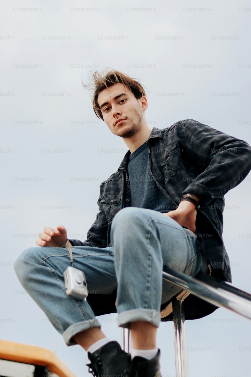 a man sitting on top of a metal pole