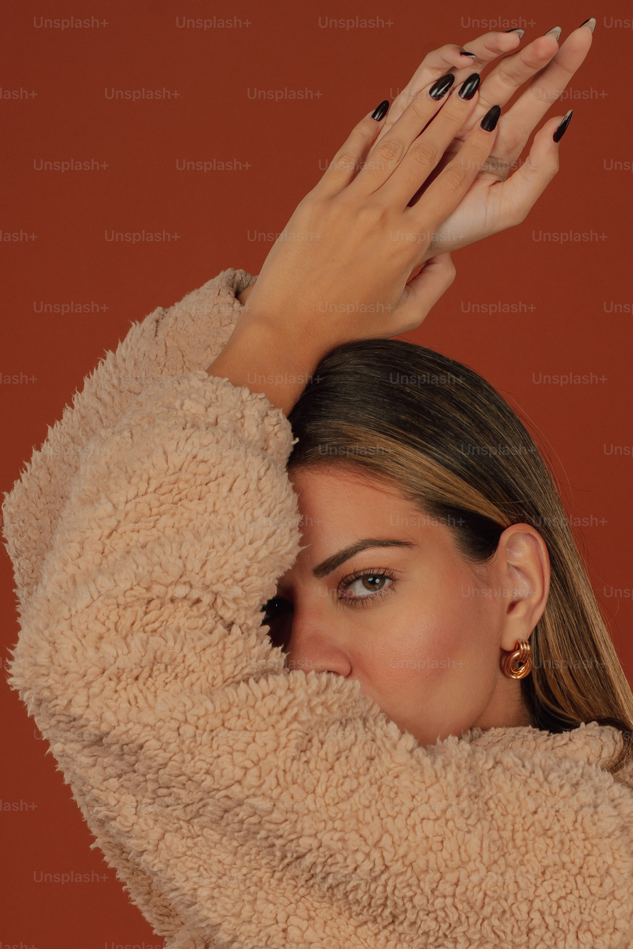 a woman in a fuzzy coat covering her face with her hands