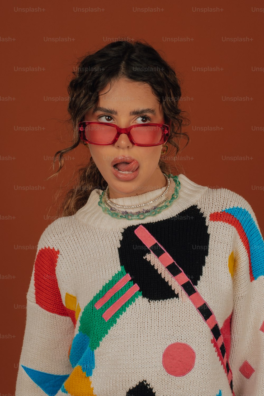 uma mulher em um suéter colorido fazendo um rosto surpreso