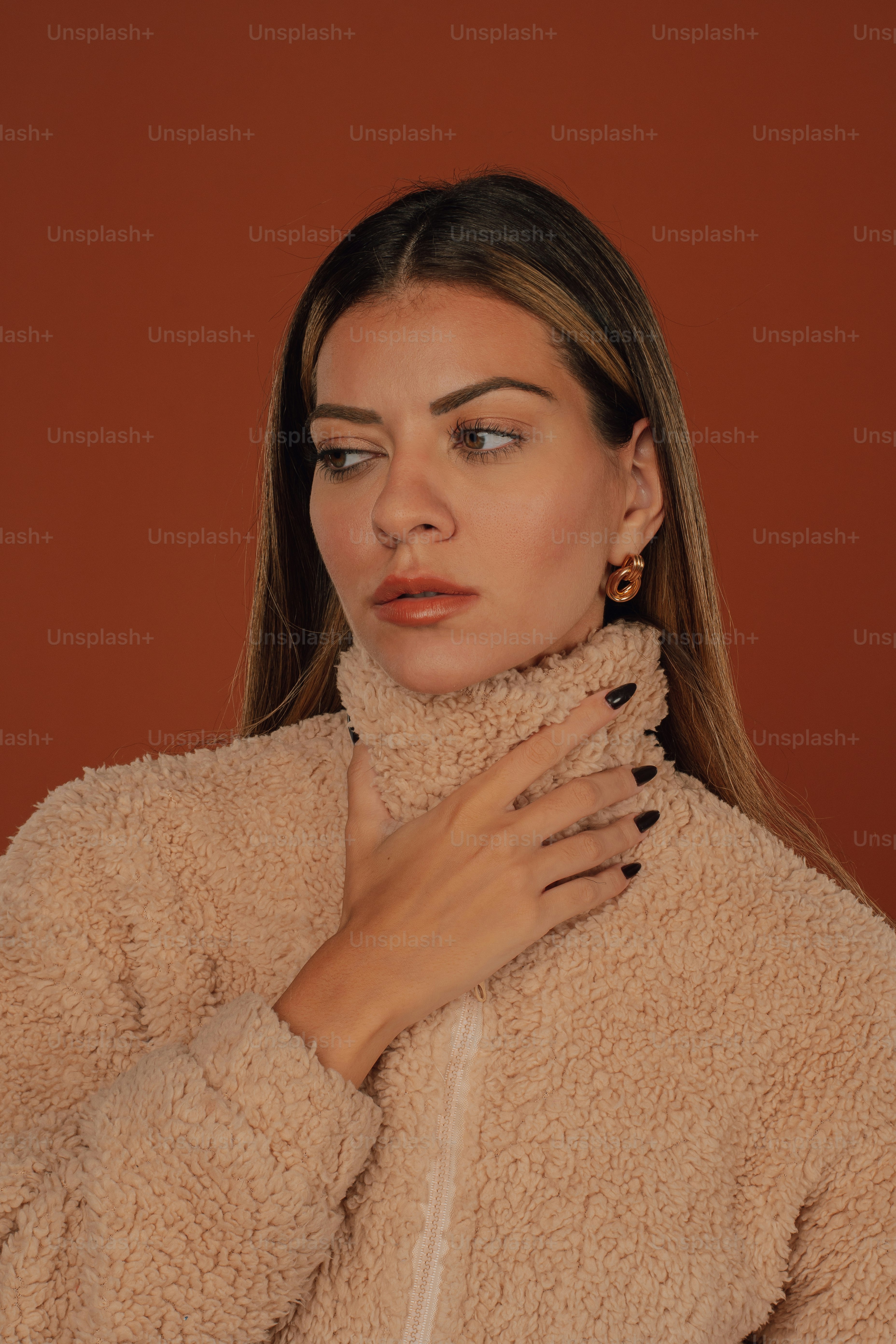 a woman wearing a tan coat and black nail polish