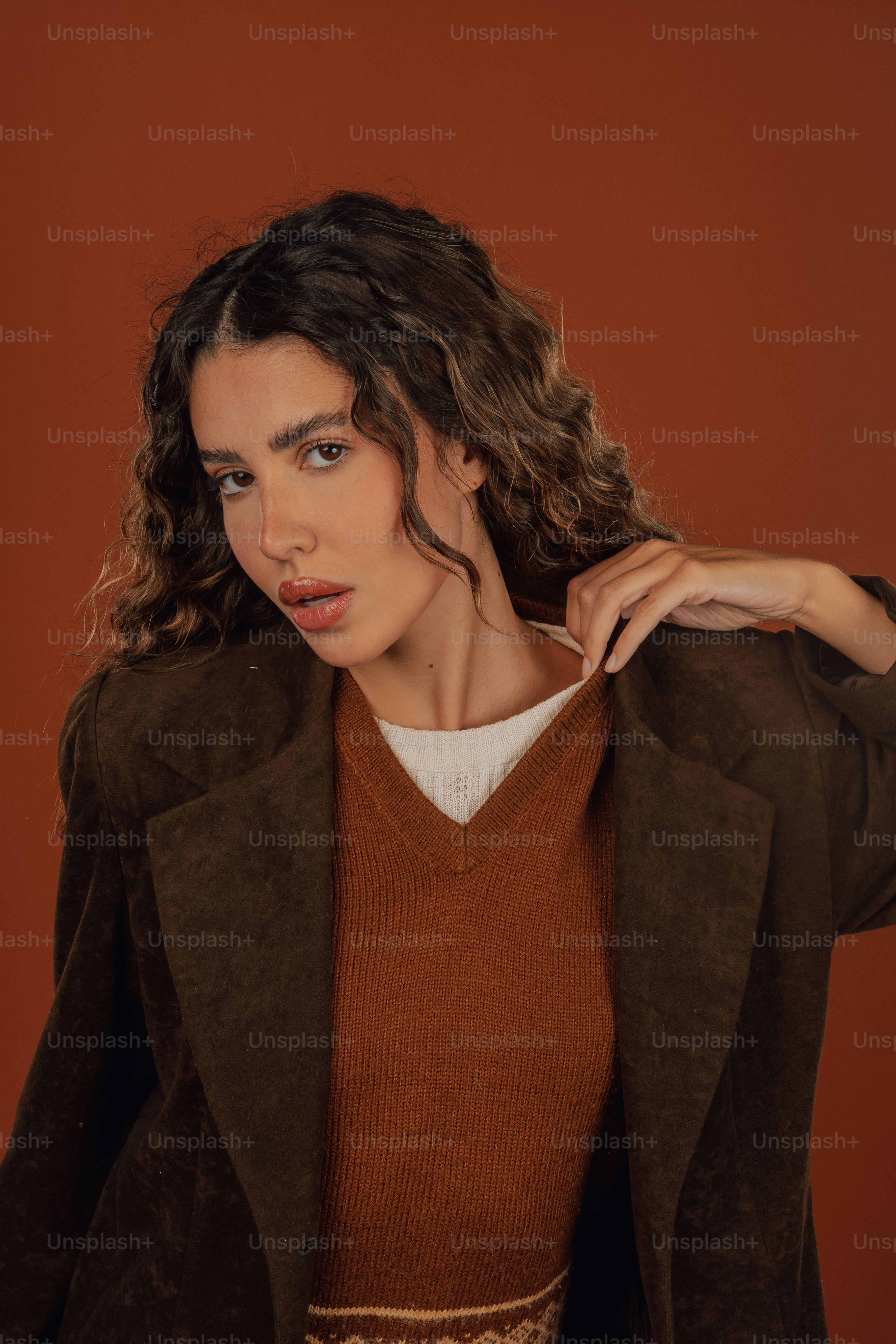 a woman with curly hair wearing a brown jacket