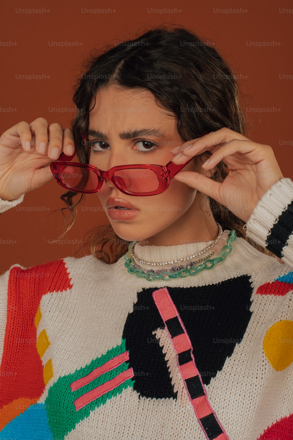 uma mulher que veste um suéter colorido e óculos vermelhos