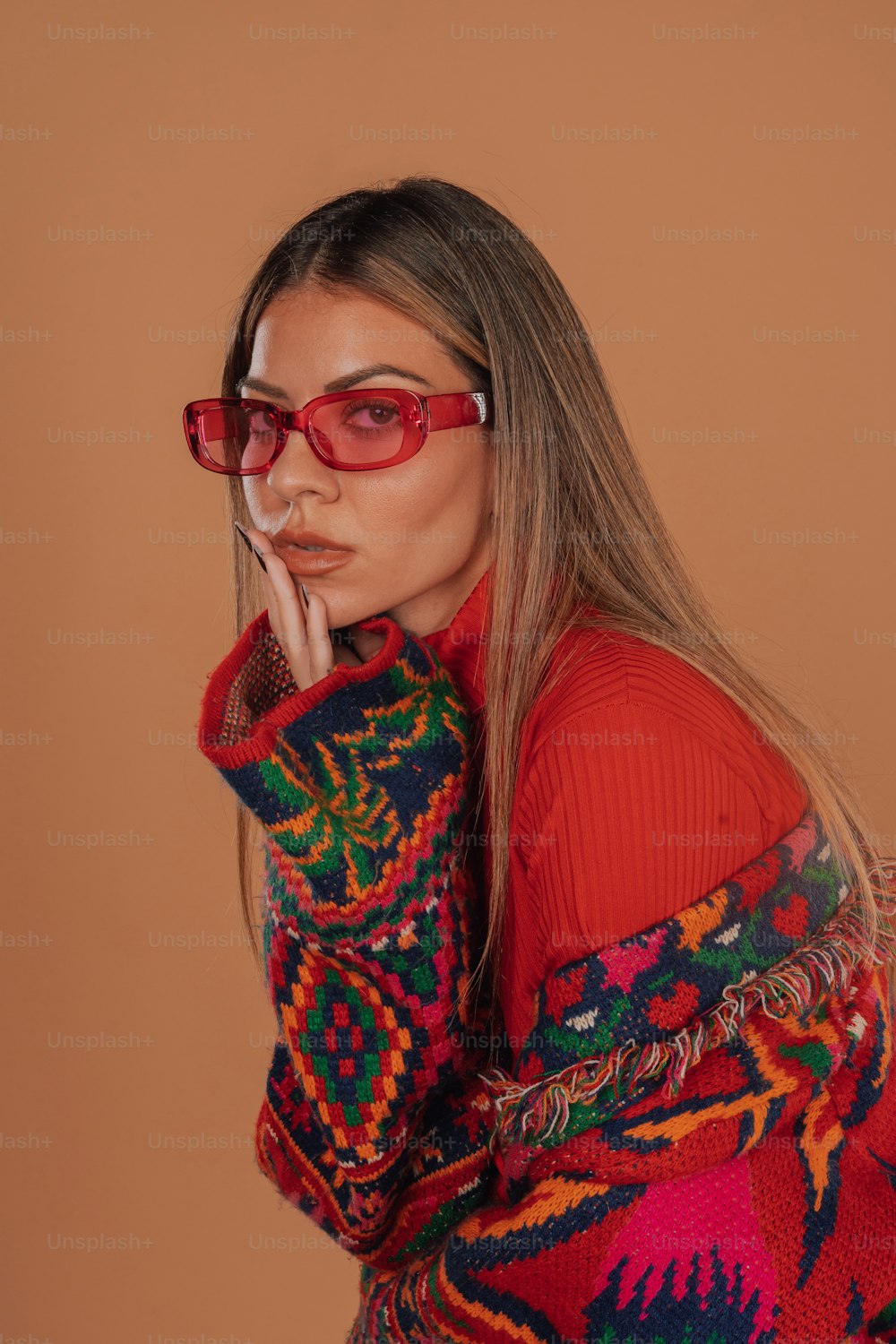 Una mujer con gafas rojas y un suéter colorido