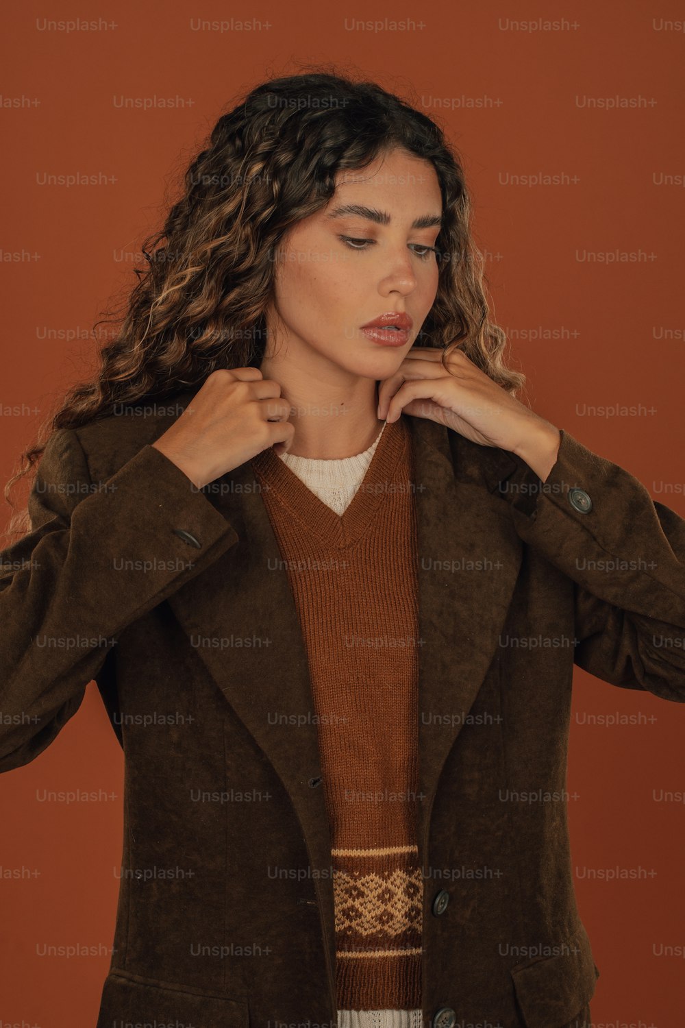 a woman wearing a brown jacket and a brown sweater