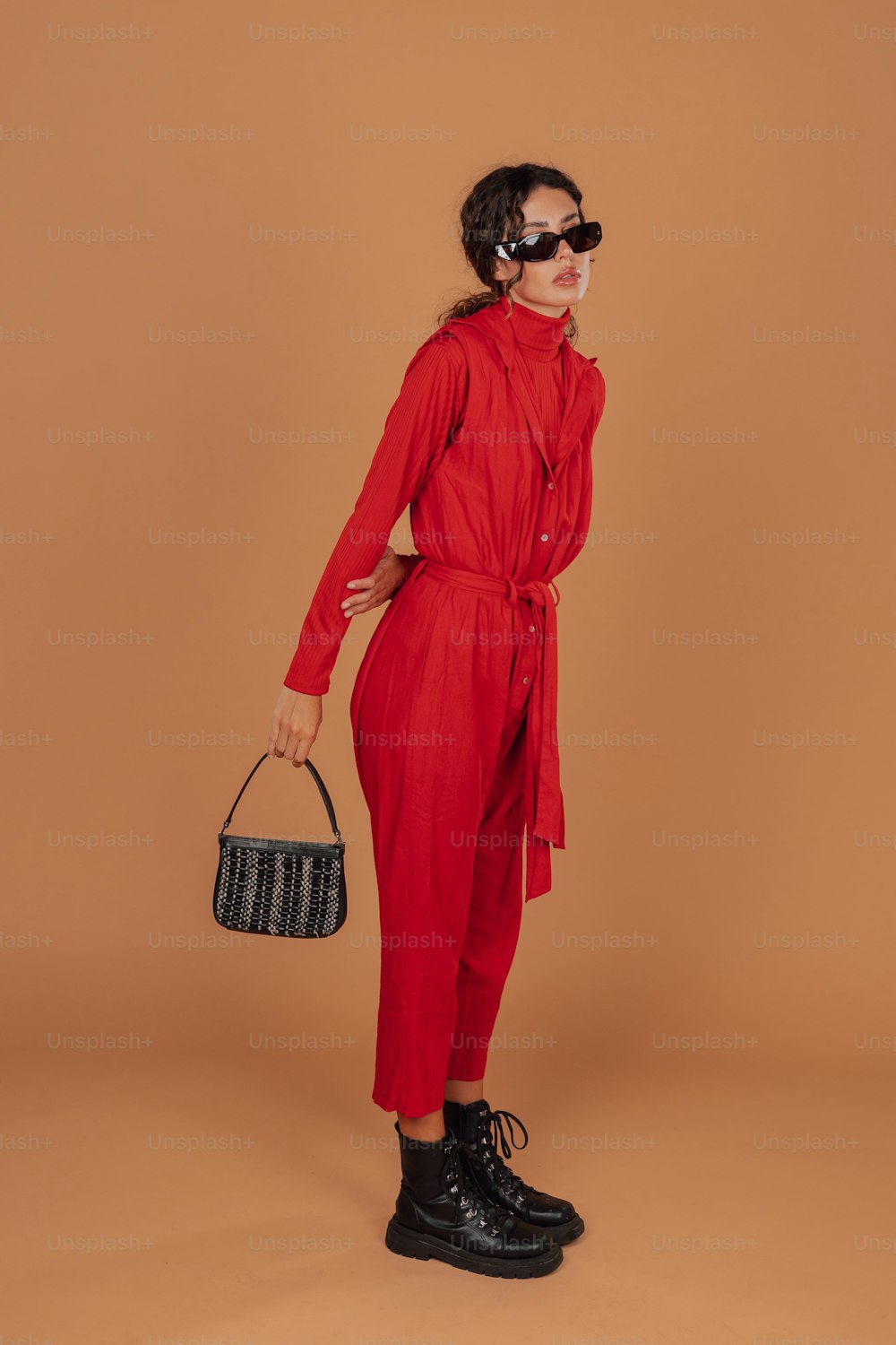 黒い財布を持つ赤いジャンプスーツを着た女性