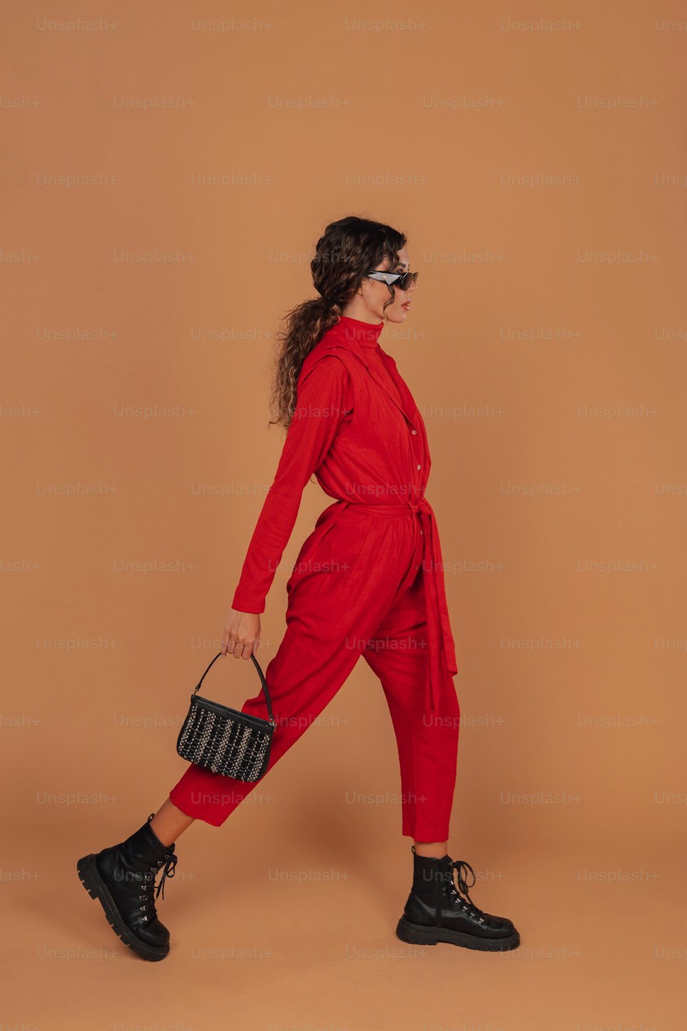 a woman in a red jumpsuit holding a black purse