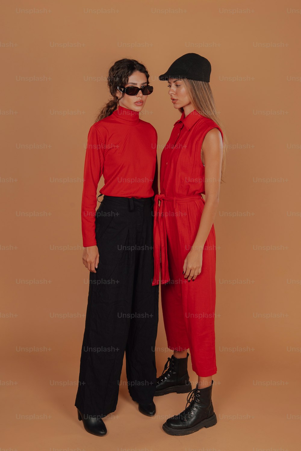 two women standing next to each other wearing red shirts and black pants