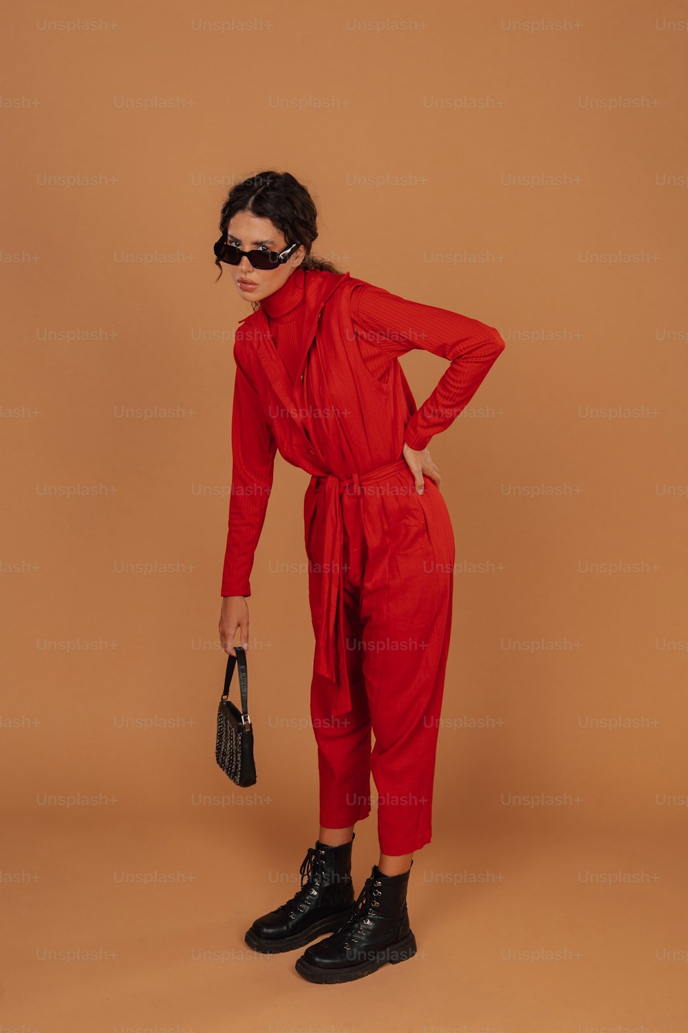 a woman wearing a red jumpsuit and black shoes