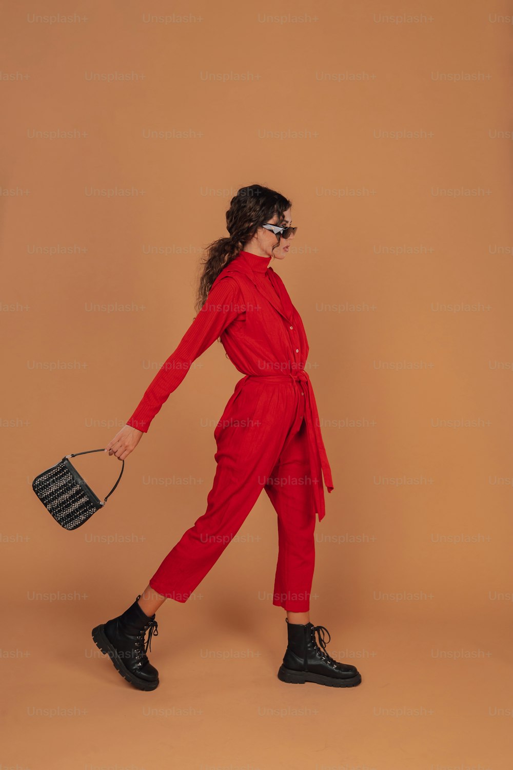 Une femme en combinaison rouge tenant un sac à main noir