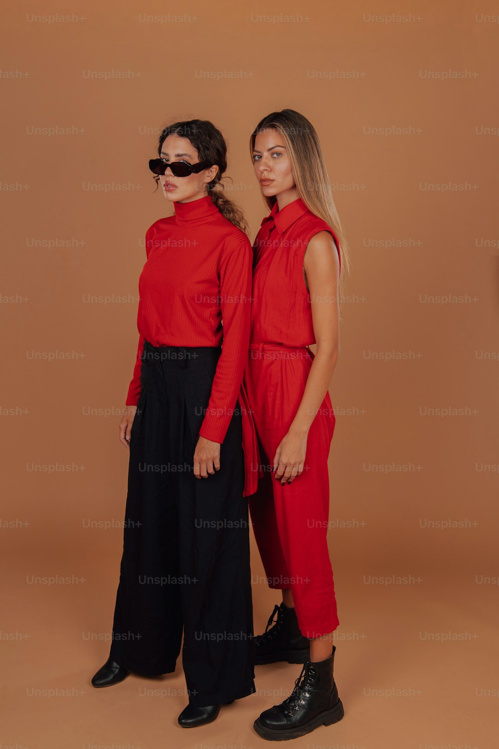 two women standing next to each other wearing red shirts and black pants