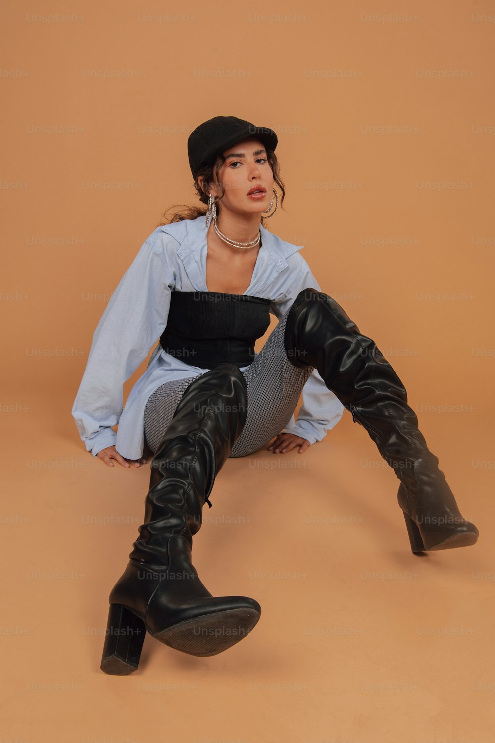 a woman sitting on the ground wearing black boots
