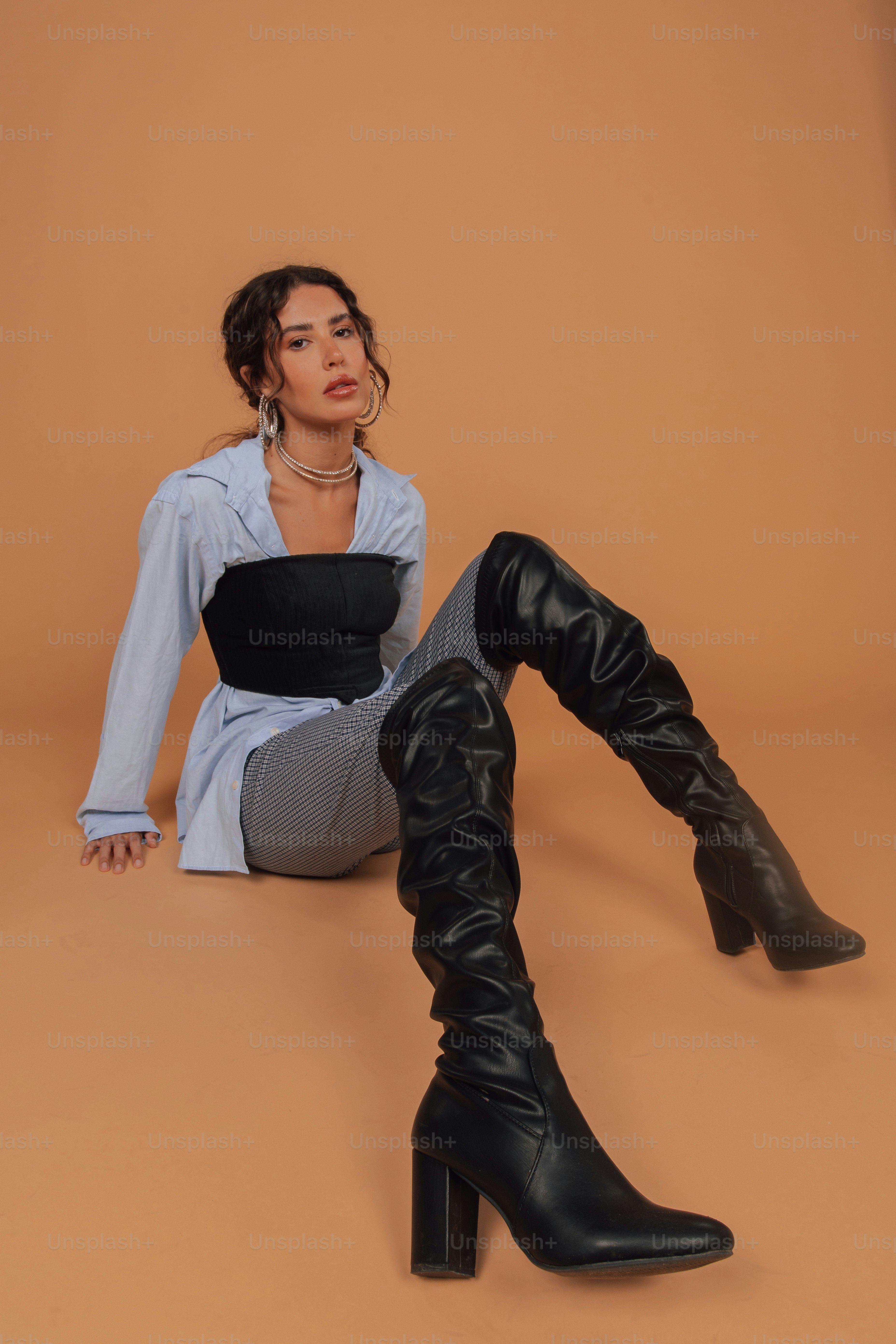 a woman sitting on the ground wearing black boots