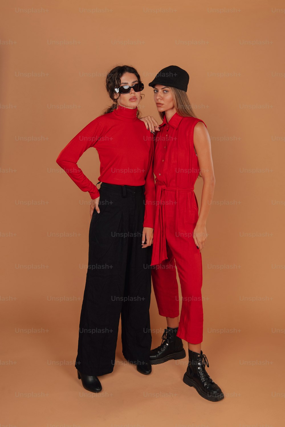 Zwei Frauen stehen nebeneinander vor braunem Hintergrund