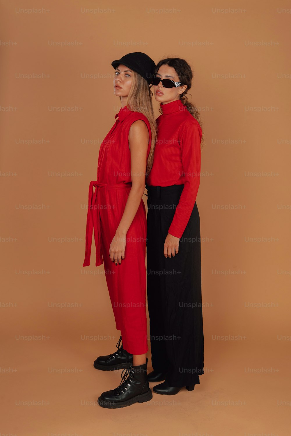 two women standing next to each other in front of a brown background