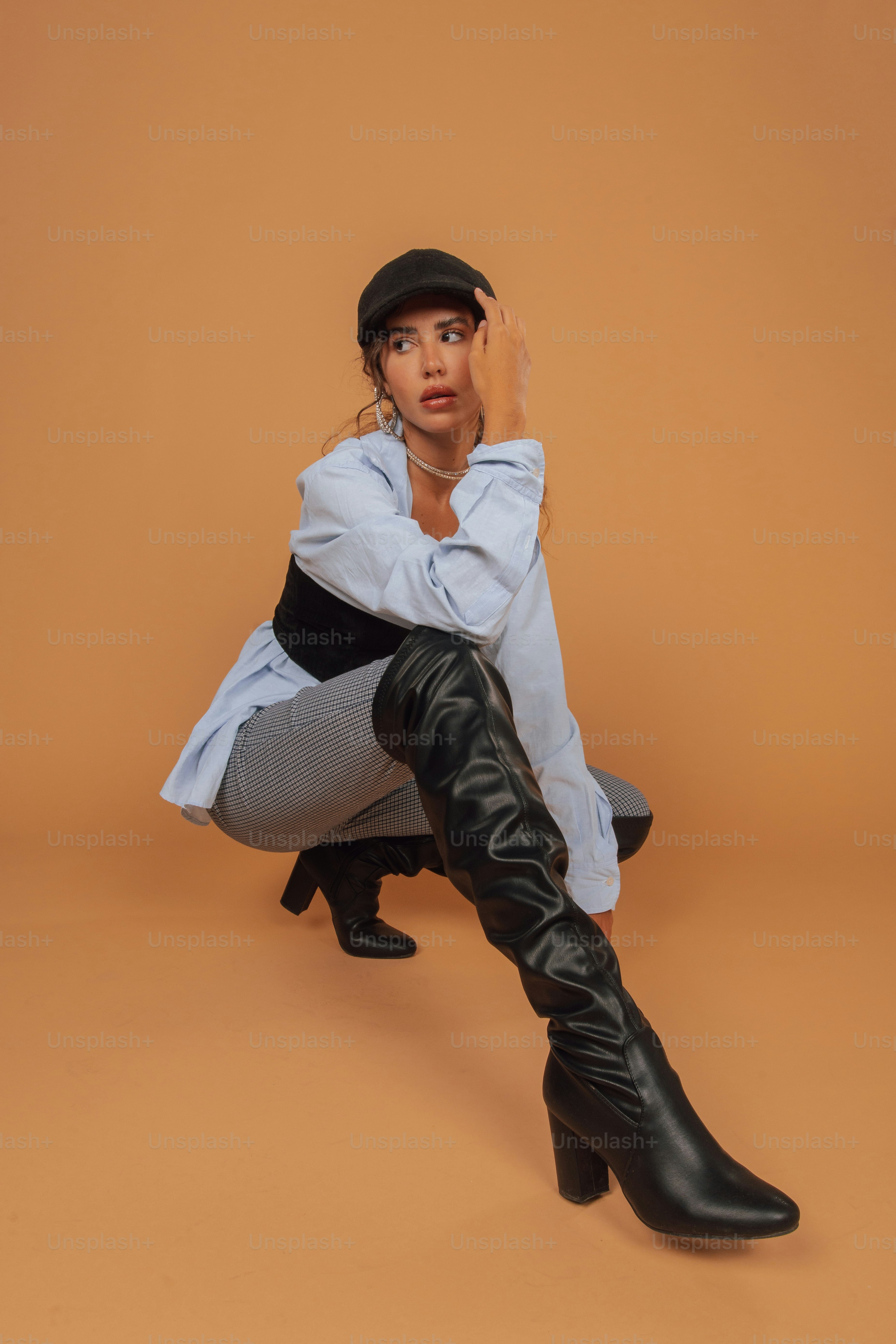 A woman sitting on the ground wearing black boots photo – Hat Image on ...