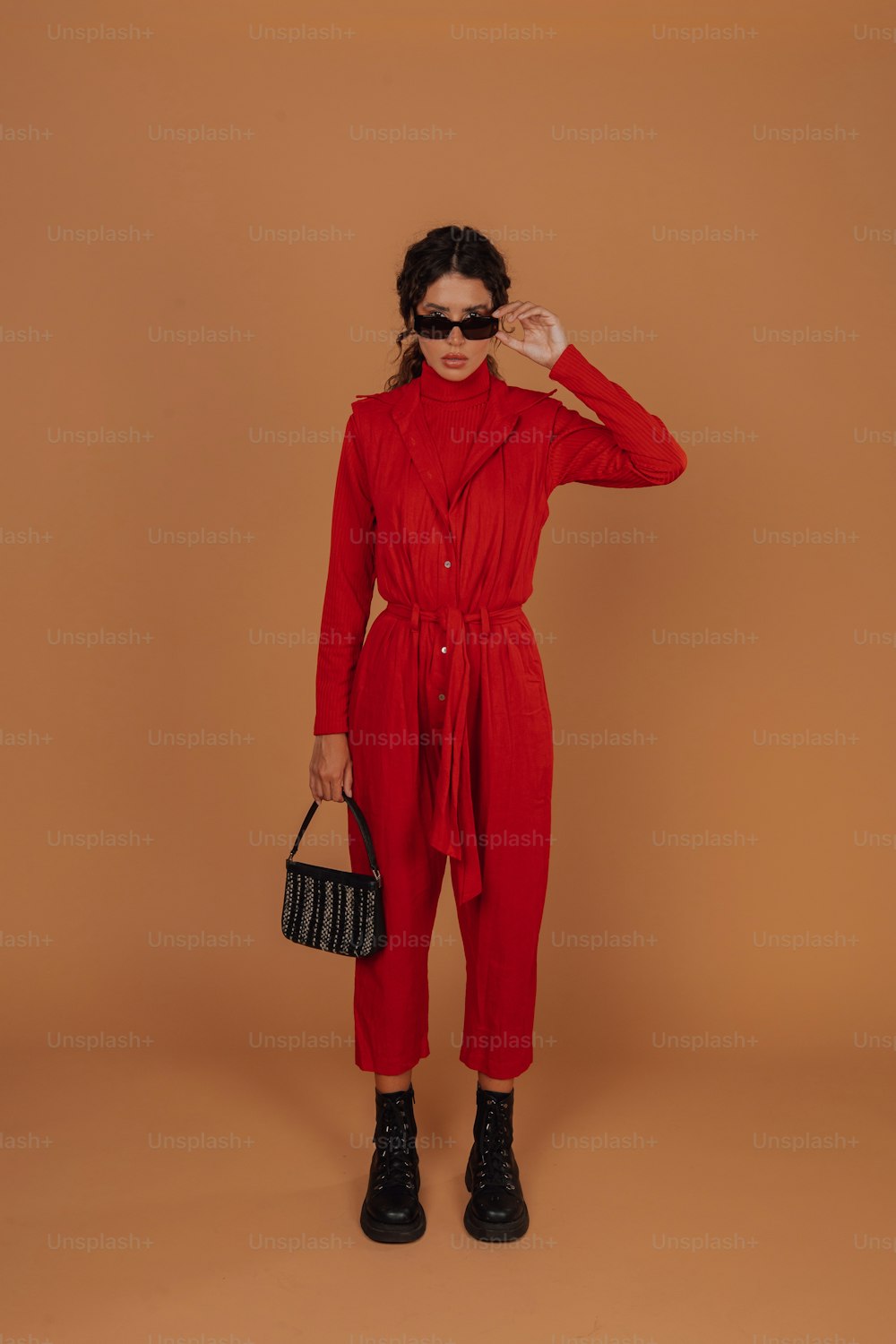 a woman in a red jumpsuit holding a handbag