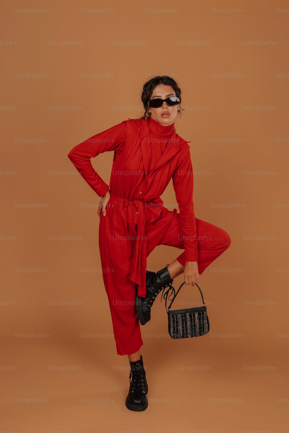 a woman in a red jumpsuit holding a black purse