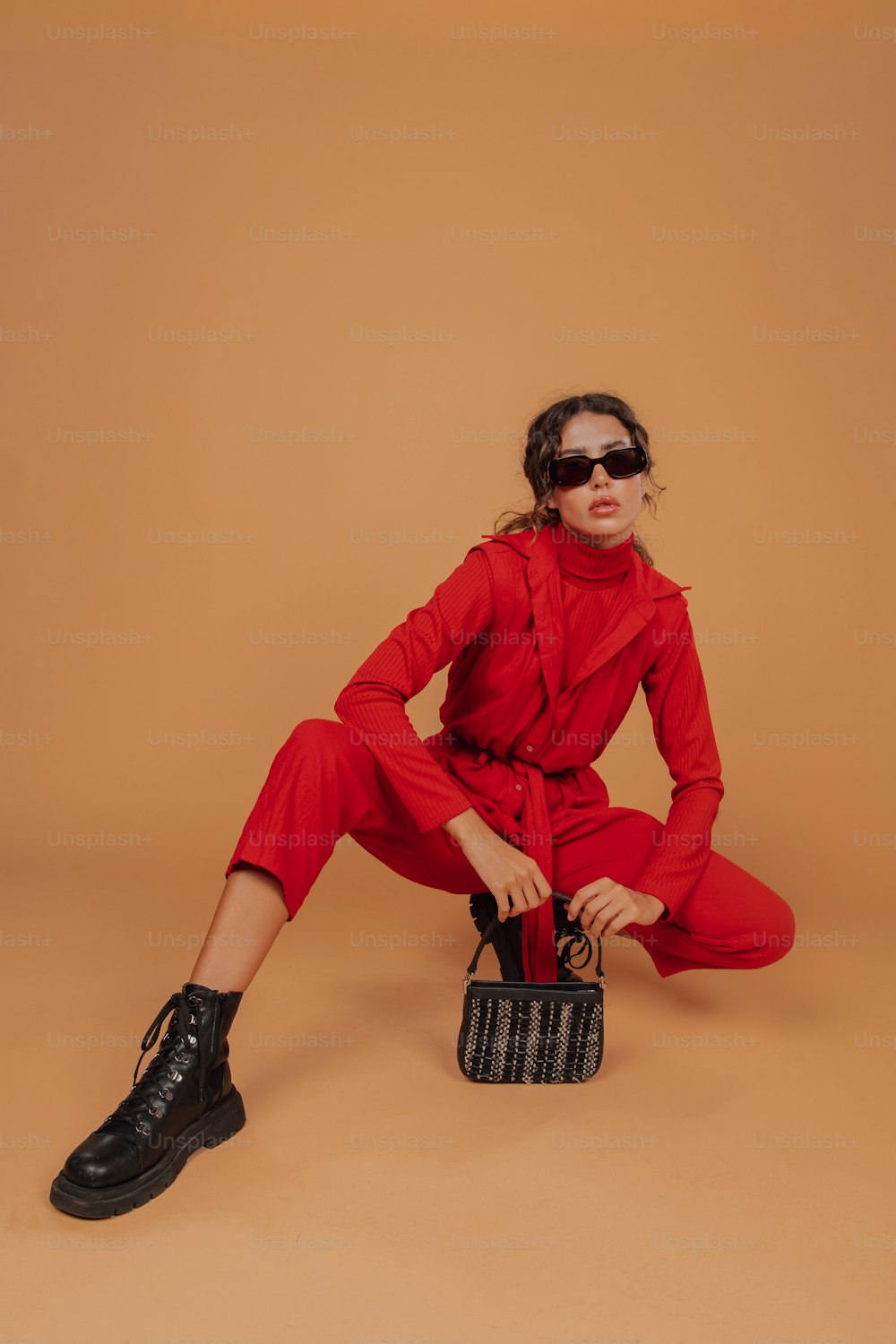 a woman in a red jumpsuit holding a purse