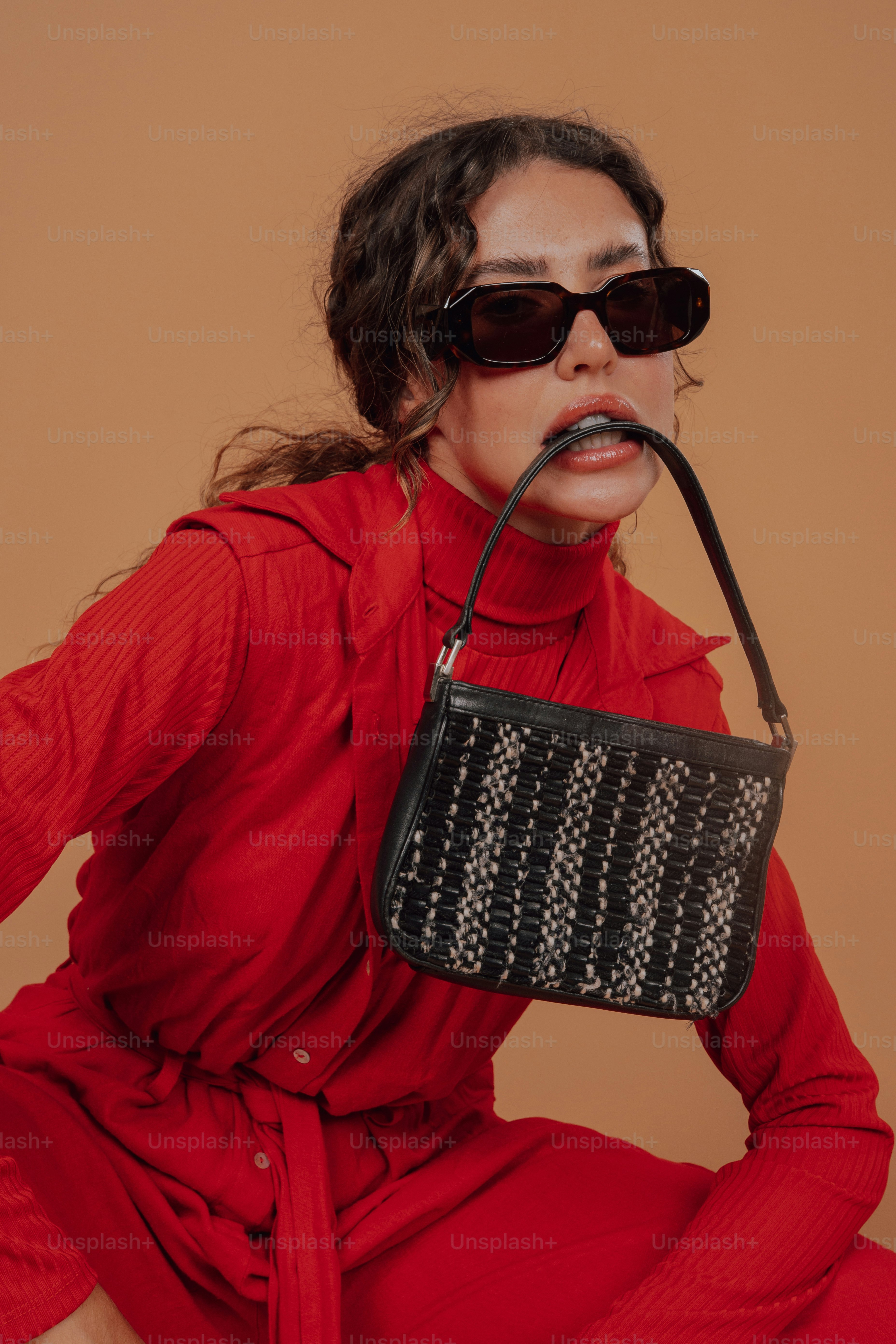 Une femme en robe rouge tenant un sac à main noir