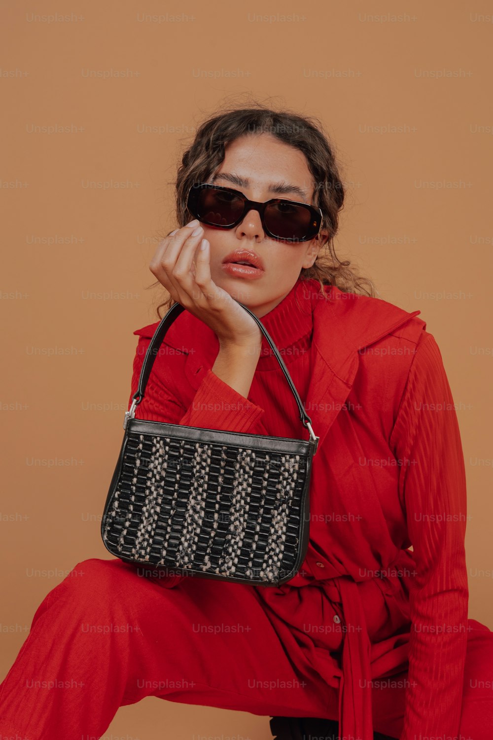 Una mujer con una camisa roja sosteniendo un bolso negro