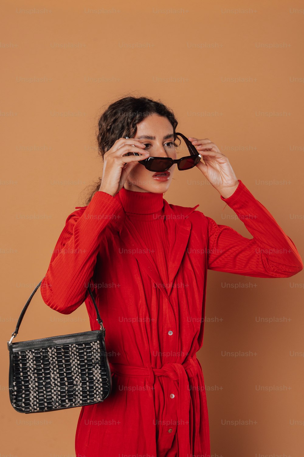 Une femme en robe rouge tenant un sac à main noir