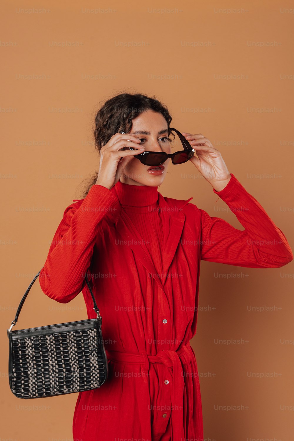 a woman in a red dress holding a black purse