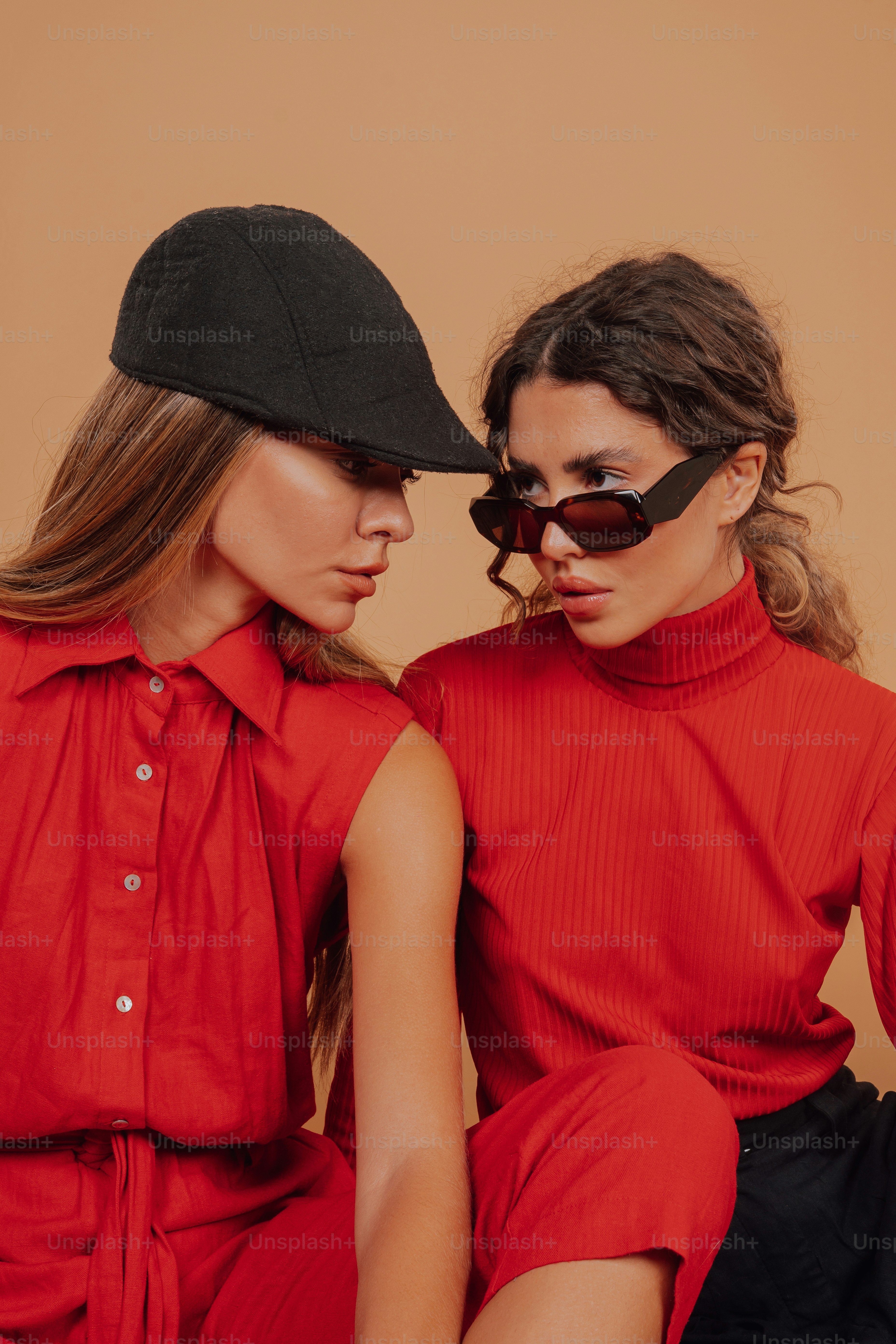 two women sitting next to each other wearing red outfits